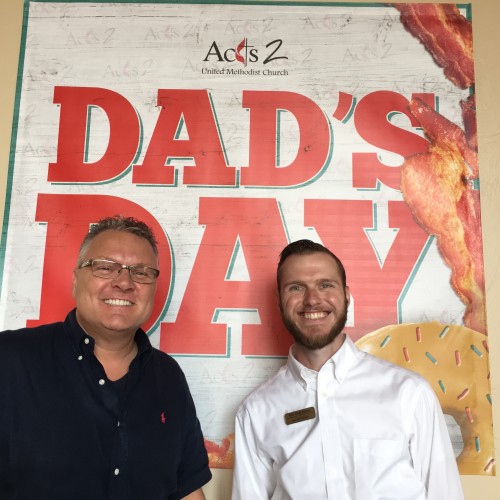 Mark and Andy standing in front of the Dad's Day banner